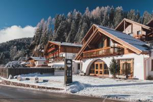 un lodge en las montañas con nieve en el suelo en Sayonara Nature & Wellness Hotel, en San Martino di Castrozza