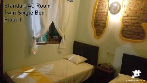 ein kleines Schlafzimmer mit einem Bett und einem Fenster in der Unterkunft Rumah Gandrung in Ngabean