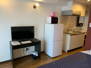eine kleine Küche mit einem Kühlschrank und einem Schreibtisch mit einer Mikrowelle in der Unterkunft Clean Hotels in Higashimachi in Naha