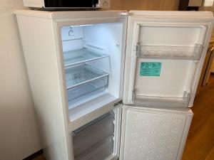 an empty refrigerator with its door open in a kitchen at Clean Hotels in Higashimachi in Naha