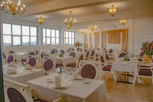 uma sala de banquetes com mesas e cadeiras brancas e lustres em FAYA Hotel em Douala