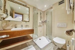 a bathroom with a shower and a toilet and a sink at Hotel Römerhof in Fusch an der Glocknerstraße