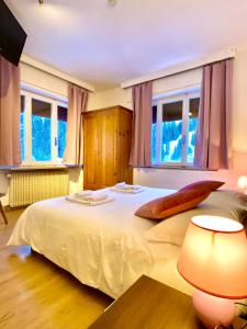 a bedroom with a large white bed and windows at Hotel B&B Lorenzini Ski in Selva di Cadore