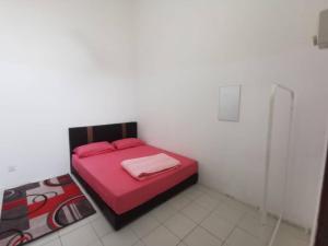 a bedroom with a red bed in a white room at AS'CATTLEYA HOMESTAY in Sepang