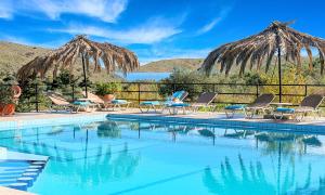 a swimming pool with chairs and umbrellas at Welcome Apts in Georgioupolis