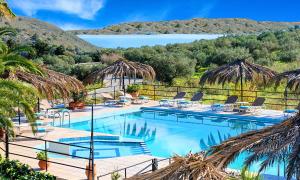 a swimming pool with chairs and a view of the ocean at Welcome Apts in Georgioupolis