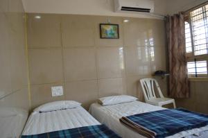 a bedroom with two beds and a chair and a window at Mourya Deluxe A/C Lodge in Chitradurga