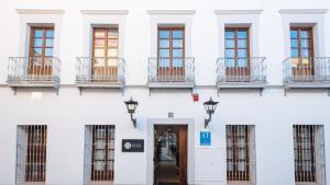 a white building with a door and windows at Lola de Triana Apartments in Seville