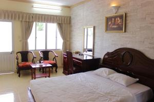 a bedroom with a bed and a desk and chairs at Lam Son Hotel in Vung Tau