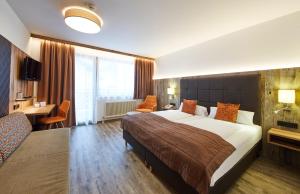 Una habitación de hotel con una cama grande y un sofá. en Hotel Römerhof, en Fusch an der Glocknerstrasse