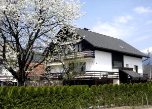 a white and black house with a flowering tree at Apartments Lenardic in Bled