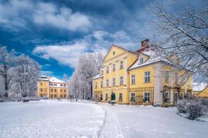 un gran edificio amarillo con nieve en el suelo en Pałac Łomnica Karkonosze - Schloss Lomnitz Riesengebirge, en Jelenia Góra