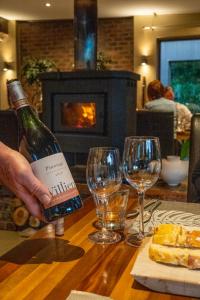 una persona sosteniendo una botella de vino en una mesa con copas en Lily Pond Country Lodge, en The Crags