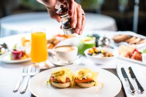 uma mesa com um prato de comida para o pequeno-almoço e uma pessoa a polvilhar molho em Saxon Hotel, Villas & Spa em Joanesburgo