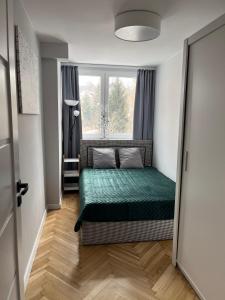 een kleine slaapkamer met een bed en een raam bij Apartament Wspomnienie in Duszniki Zdrój