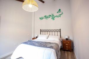 Habitación blanca con cama y lámpara de araña. en APARTAMENTOS LA VIEJA IMPRENTA, en Sigüenza