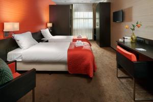 a hotel room with two beds and a desk at Hotel Babylon Heerhugowaard - Alkmaar in Heerhugowaard