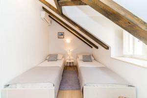 a attic room with two beds and two windows at Holiday Home Kazerma in Dubrovnik