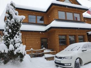 une maison enneigée avec une voiture garée devant elle dans l'établissement Izba w centrum miasta, à Zakopane