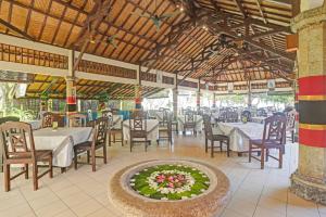 un restaurant avec des tables et des chaises et un arrangement floral dans l'établissement Collection O 90805 Aditya Beach Resort And Spa, à Lovina