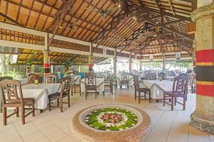 ロビナにあるCollection O 90805 Aditya Beach Resort And Spaのテーブルと椅子、フラワーアレンジメント付きのレストラン