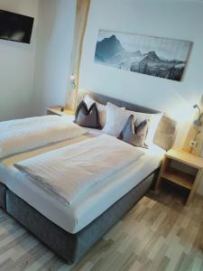 a bedroom with a large bed with white sheets and pillows at Hotel Gasthof Klammstein in Dorfgastein