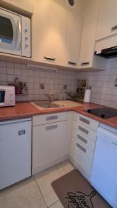 a kitchen with white cabinets and a sink at Superbe appartement à 50m des pistes parking privé in La Toussuire