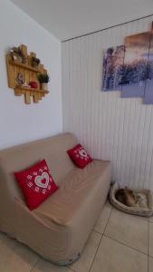 um sofá num quarto com duas almofadas vermelhas em Superbe appartement à 50m des pistes parking privé em La Toussuire