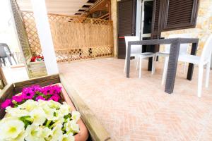 a patio with two chairs and a table and flowers at Giardini Sausari Residence in Punta Prosciutto