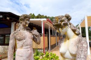 a statue of two men standing in front of a building at Giardini Sausari Residence in Punta Prosciutto