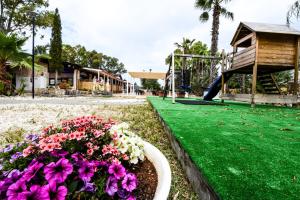 a park with flowers and a playground with a slide at Giardini Sausari Residence in Punta Prosciutto