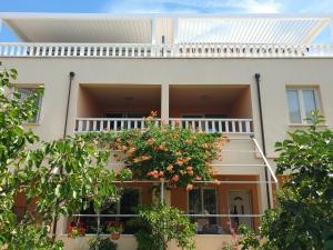 a white house with a balcony with flowers on it at Apartments Tare in Vodice