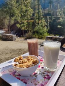 una bandeja con un tazón de comida y un vaso de leche en The Riverwoods - Cafe & Stay, en Kasol