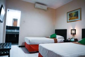 A bed or beds in a room at Helios Hotel Malang