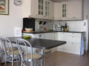 a kitchen with white cabinets and a black table and chairs at Résidence Green Village in La Grande Motte