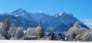 a house in the snow with mountains in the background at Hotel Schatten in Garmisch-Partenkirchen +188 photos