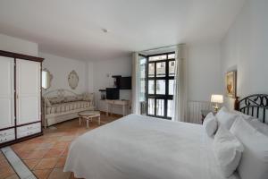 a bedroom with a white bed and a living room at Hotel Rosa De oro in Granada