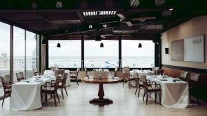 a dining room with tables and chairs and the ocean at Hotel Villa Rosario II, Edificio Moderno in Ribadesella