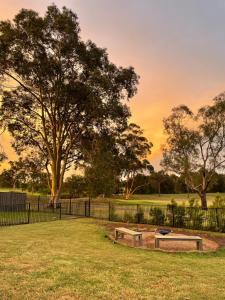a park with a bench and a fence and trees at Stones Throw Hunter Valley 3mins to Cellar Doors in Cessnock