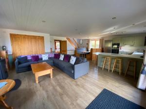 a living room with a blue couch and a kitchen at Ghillies Lodge Crianlarich in Crianlarich