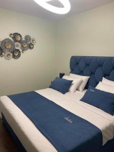 een groot bed met een blauw hoofdeinde en kussens bij Essy's Apartment in Korçë +15 foto's