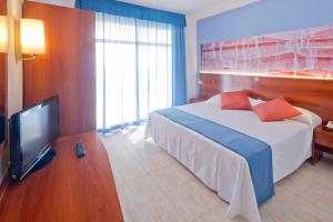 a hotel room with a bed and a television at GHT S'Agaró Mar Hotel in Sant Feliu de Guíxols