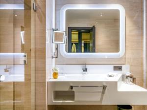 a bathroom with a white sink and a mirror at BERDS Chisinau Mgallery Hotel Collection in Chişinău