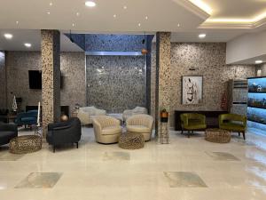 un vestíbulo con una zona de espera con sillas y mesas en Хотелски комплекс Белият кон en Targovishte