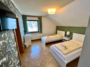 a room with two beds and a flat screen tv at Pension Lambrecht in Sankt Lambrecht