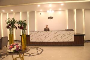 a man standing behind a reception desk in a lobby at Jewel Assiut Hotel in Asyut