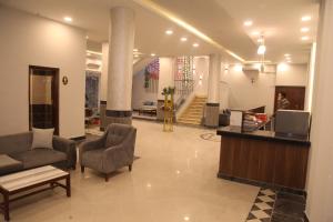 a lobby with a couch and chairs and a tv at Jewel Assiut Hotel in Asyut