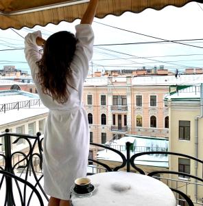 Una mujer con un vestido blanco parada en un balcón en Anabel at Nevsky 88, en San Petersburgo