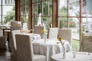 a dining room with white tables and chairs and windows at Adler Spa Resort Dolomiti in Ortisei