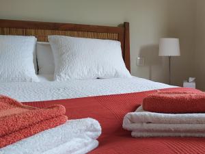 Una cama con toallas rojas y blancas. en Finca Las Morenas en Yunquera